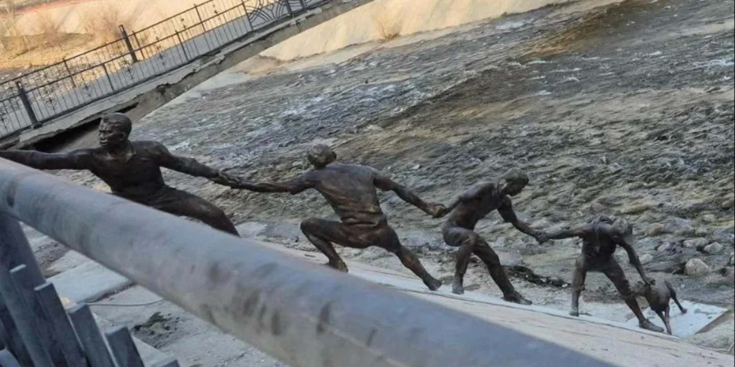 Une statue en bronze représentant plusieurs hommes formant une chaîne humaine pour le sauvetage d'un chien.