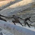 Une statue en bronze représentant plusieurs hommes formant une chaîne humaine pour le sauvetage d'un chien.