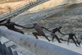 Une statue en bronze représentant plusieurs hommes formant une chaîne humaine pour le sauvetage d'un chien.