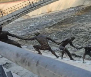 Une statue en bronze représentant plusieurs hommes formant une chaîne humaine pour le sauvetage d'un chien.