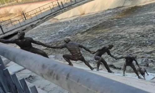 Une statue en bronze représentant plusieurs hommes formant une chaîne humaine pour le sauvetage d'un chien.