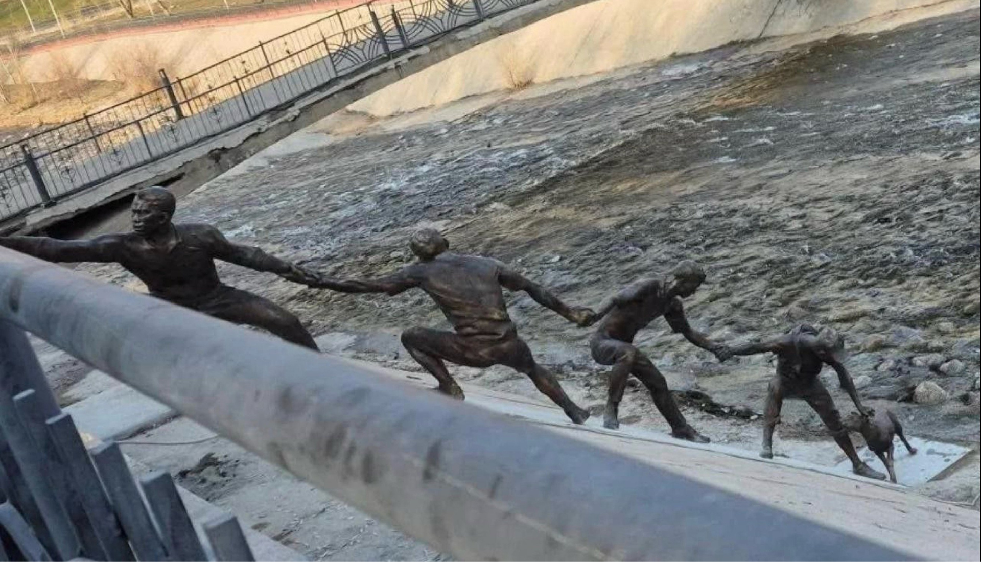 Une statue en bronze représentant plusieurs hommes formant une chaîne humaine pour le sauvetage d'un chien.